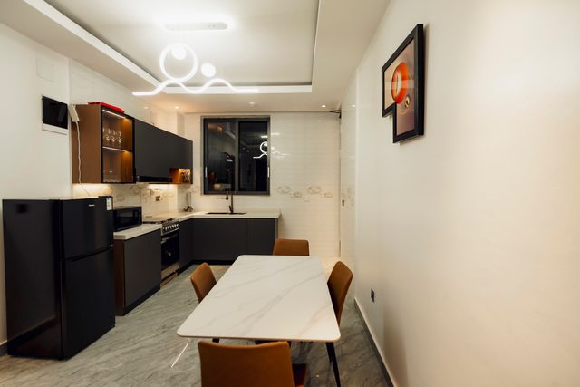 Separate kitchen with marble dining table and four leather chairs